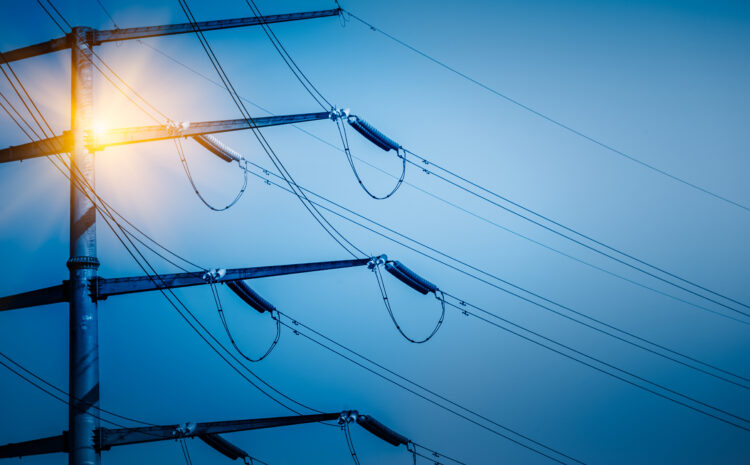 Poste de alta tensión con cables eléctricos iluminado, representando la infraestructura crítica de los servicios públicos, cuya eficiencia y seguridad pueden optimizarse mediante una gobernanza de datos efectiva.