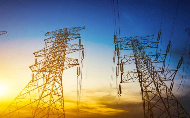 Silhouettes of two large electrical transmission towers against a vibrant sunset sky. The image represents critical power utility infrastructure and evokes the themes of transition, future planning, and financial resilience needed to navigate a decade of disruption.