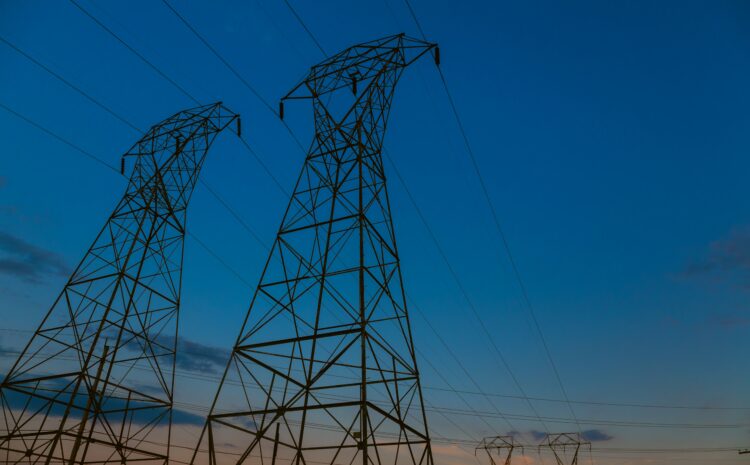High-voltage transmission towers against a sunset sky, representing critical utility infrastructure and the need for operational resilience.