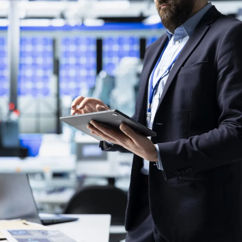 Ejecutivo financiero del sector energético revisando datos en tablet en instalación de infraestructura eléctrica, representando la transformación digital de las finanzas en empresas de servicios públicos